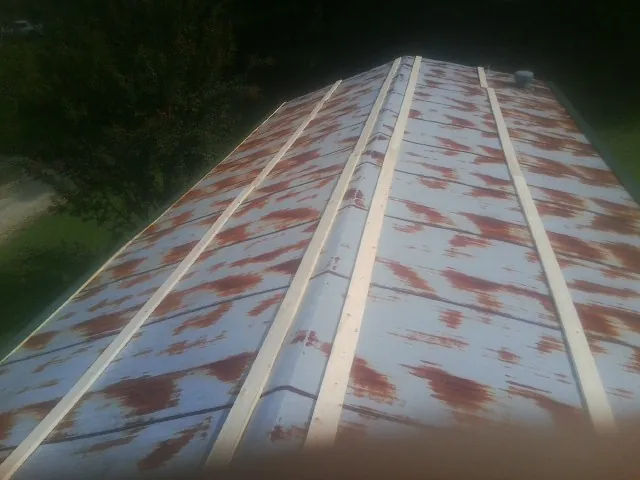 Rusted metal roof panels with new wood purlins before replacement in Greenwood